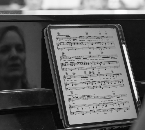Close-up of sheet music on a piano with the reflection of a teacher during an audition at The New Academy Musical Theatre Vienna